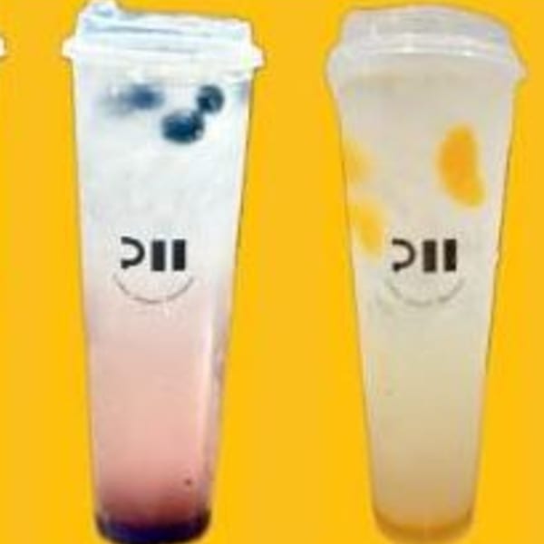 Two clear plastic cups with Pillow Talk Cafe's logo, one with blueberries, the other with mango pieces.