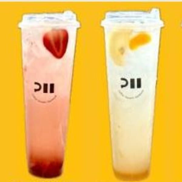 Two tall plastic cups of Pillow Talk Cafe drinks, one strawberry pink and one creamy yellow.