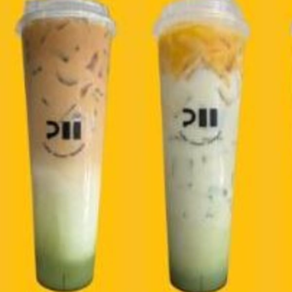 Two tall iced drinks from Pillow Talk Cafe, one brown and one green, with logos.